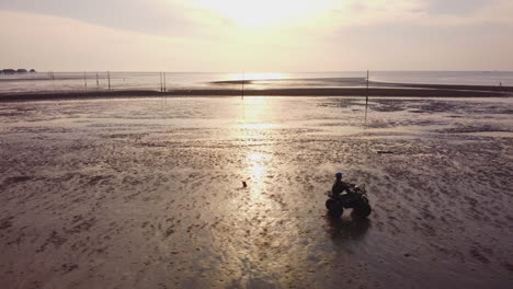 Drone-view-following-an-ATV-rider-riding-on-the-beachside-in-Bagan-Lalang