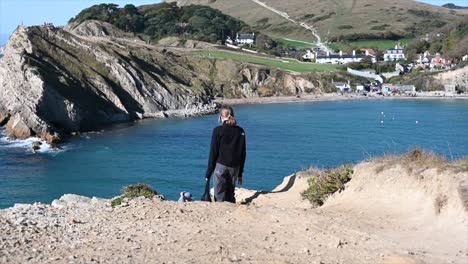 a-girl-walks-on-the-shore-of-lulworth-cave-in-the-south-of-England,-sea-with-cliffs