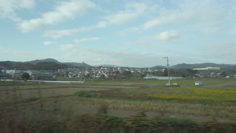 local-countryside-landscape-view-through-train-window-while-train-moving-fast-in-japan-daytime,-natural-view-on-the-side-of-railway-track