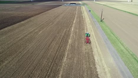An-aerial-view-at-height-of-a-tractor-as-it-makes-it's-way-down-a-field-tilling-the-land-to-prepare-it-for-the-next-crop