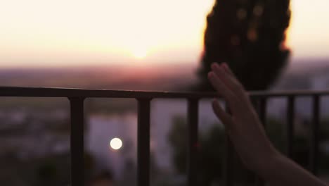 slow-motion-shot-of-a-woman-running-her-hand-along-a-railing-during-sunset