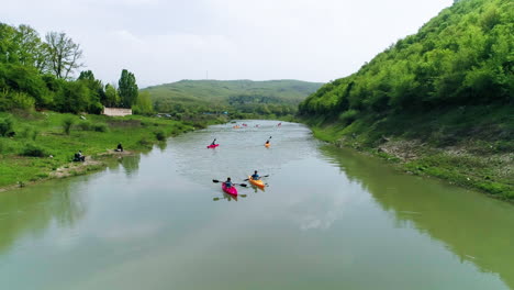 Group-of-friends-kayak-towards-frame,-aerial-pullback-along-river-Drin-in-Kosovo
