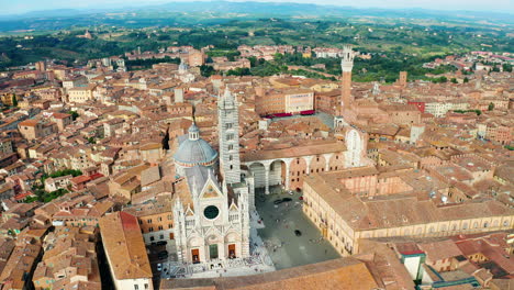 Right-to-left-aerial-trucking-shot-of-the-Torre-del-Mangia-and-the-rooftops-of-Siena,-Tuscany,-Italy