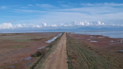 Aerial-overhead-drone-footage-of-Axios-river-and-a-dirt-road-in-Thessaloniki,Greece-of-a-river-delta-leading-to-meditteranen-sea-and-creating-a-swamp-like-footprint
