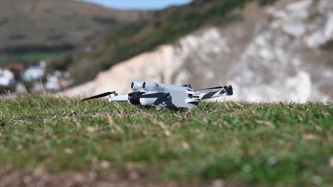 A-grey-drone-is-on-grass,-ready-to-take-off,-filmmaking-gear,-technology