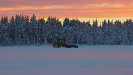 Early-morning-Norbotten-tractor-snow-blower-preparing-woodland-ice-track-under-orange-sunrise