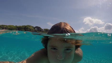 Under-water-selfie-of-beautiful-cute-little-red-haired-girl-holding-breath-while-floating-in-transparent-sea-water