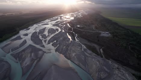 Fliegen-über-Den-Waimakariri-Braided-River-In-Richtung-Sonnenuntergang-Mit-Lichtstrahlen-In-Christchurch,-Canterbury,-Neuseeland