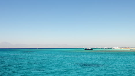Orange-Bay-Beach-in-Hurghada,-Egypt-with-crystal-clear-azure-water-and-boat-ships-with-tourists,-60-fps