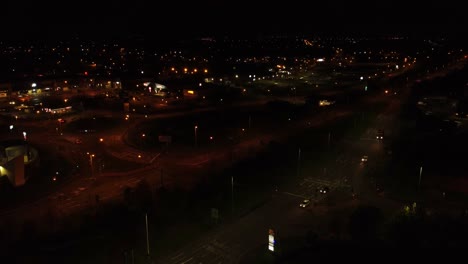 Nighttime-traffic-headlights-driving-British-rural-town-highway-intersection-aerial-view