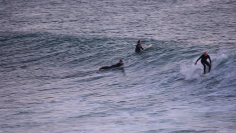 Amateur-surfer-rides-glassy-ocean-wave-on-a-fun-surfboard-entering-the-night-in-Estoril,-Cascais