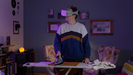 Young-adult-female-ironing-clothes-in-living-room-wearing-metaverse-virtual-reality-goggles
