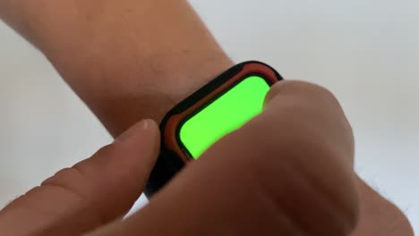 A-man-uses-a-smart-watch-with-a-chromakey-on-a-green-screen-and-touch-him