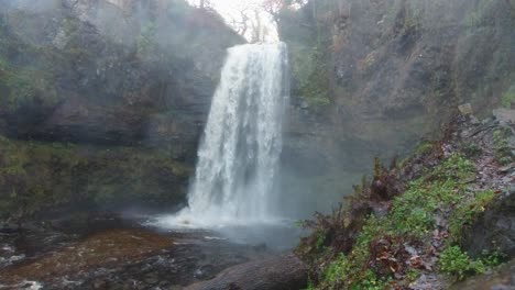 Unglaublicher-Wasserfall,-Der-Unten-Auf-Den-Fluss-Stürzt-Und-Das-Kameraobjektiv-4k-Besprüht