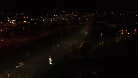 Nighttime-traffic-headlights-driving-British-town-highway-intersection-aerial-view