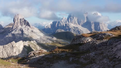 Mountain-landscape-aerial-reveal,-Monte-Pelmo-mountain-peak-covered-in-clouds-with-alpine-valley-below,-Dolomites