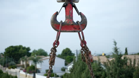 Industrial-chained-crane-hoist-with-weathered-red-paint-lifting-heavy-goods
