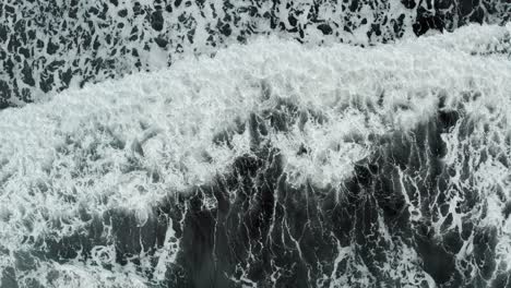 Black-and-white-patterns-of-nature-as-wave-crashes-onto-black-sand-beach