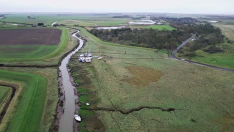 Swooping-aerial-footage-flying-towards-boats-showing-river-estuary-and-farmland