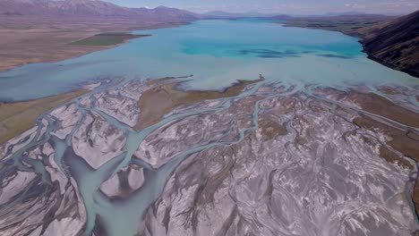 aerial-flying-over-the-braided-Godley-river-flying-towards-Lake-Tekapo-mouth-with-the-mountains-in-the-background