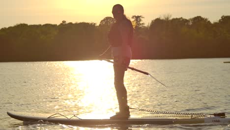 Frau-Standup-Paddle-Boarding-In-Sonnenuntergang-Seitenansicht-Nach-Slomo