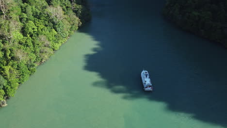 Aerial-shot-of-long-tail-tourism-boat-on-a-small-tropical-island-with-blue-water