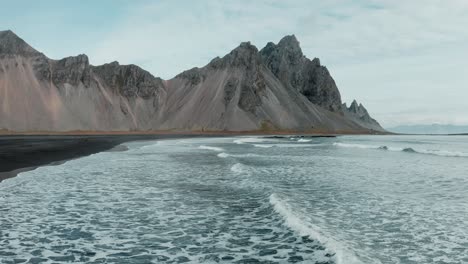 Low-aerial-over-moody-Stokksnes-beach,-view-of-Vestrahorn-mountain-,-Iceland
