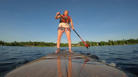 Frau-Standup-Paddle-Boarding-Winkel-Von-Der-Spitze-Des-Boards-Bei-Sonnenuntergangsbeleuchtung