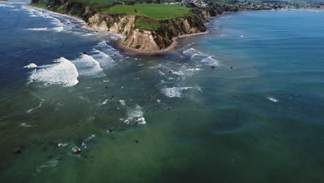 Schaumige-Wellen,-Die-Am-Steinigen-Ufer-Des-Maketu-strandes-Auf-Der-Nordinsel,-Neuseeland,-Spritzen---Luftdrohnenaufnahme