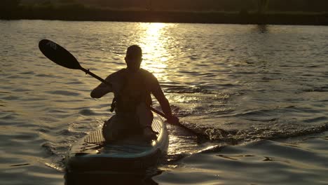Hombre-Paddle-Board-Sentado-En-El-Profundo-Atardecer-En-El-Lago-Slomo-Closeup