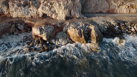 Bird-s-Eye-Shot-Of-Small-Waves-Crashing-On-Rocks-In-Blue-Sea,-Penon,-Mexico