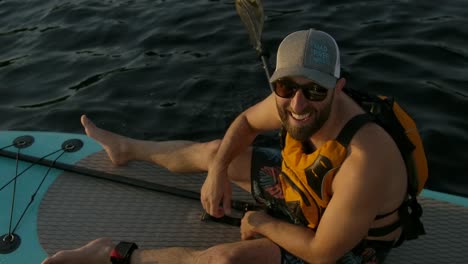 happy-man-paddle-boarder-thumbs-up-slomo-sunset-closeup