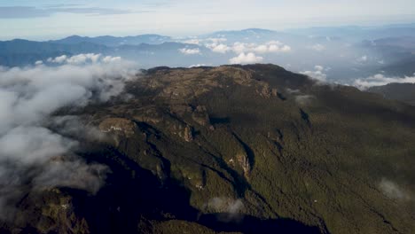 Rocky-mountain-peak-rises-above-clouds,-Papua-New-Guinea-landscape-aerial
