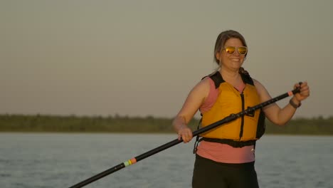 happy-pretty-girl-paddle-boarding-closeup-sunset-smiling-slomo