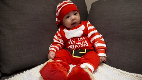 Adorable-Cute-Two-Month-Old-Baby-In-Festive-Red-Christmas-Outfit-Sitting-On-Couch-And-Yawning