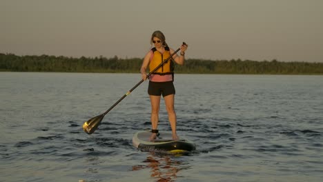 pretty-girl-paddle-boarding-into-sunset-light-slomo
