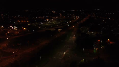 Nighttime-traffic-headlights-driving-rural-British-town-highway-intersection-aerial-view