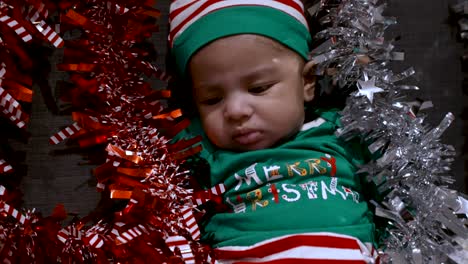 Adorable-Bebé-De-2-Meses-Con-Camisa-Verde-Feliz-Navidad-Y-Sombrero-Rodeado-De-Oropel-Rojo-Y-Plateado