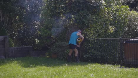 An-Old-Man-Cutting-Grass-Using-A-Manual-Grass-Cutter-At-The-Backyard