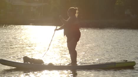 Frau-Paddle-Boarding-Im-Glitzernden-See-Sonnenuntergang-Slomo