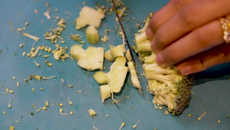 Hands-Of-Young-Asian-Woman-Carefully-Cutting-Broccoli-On-Cutting-Board