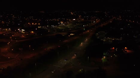 Midnight-traffic-headlights-driving-rural-British-town-highway-intersection-aerial-view