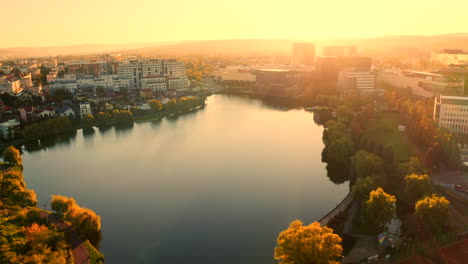Cinematic,-Establishing-Aerial-drone-shot-over-Cluj-Napoca-city,-Iulius-mall-zone,-Iulius-park,-lake-view,-sunrise