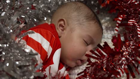 Adorable-Cute-2-Month-Old-Indian-Baby-Boy-Sleeping-Surrounded-By-Red-And-Silver-Tinsel