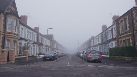 Empty-fogbound-street-in-Wales,-UK,-lined-with-cars-and-houses