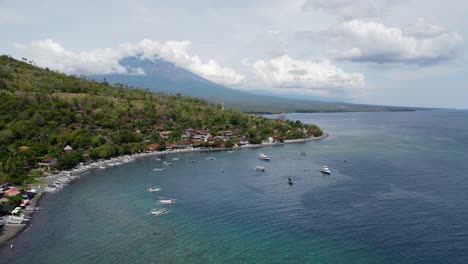 Cinematic-aerial-view-of-the-Balinese-coastal-town-Amed-Beach-with-Mount-Agung-in-the-distance