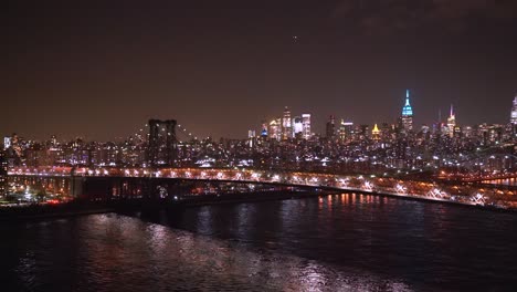 Williamsburg-Bridge-against-the-backdrop-of-East-River-and-Manhattan-at-night