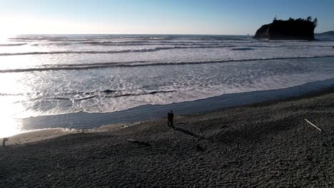 Aerial-shot-of-couple-standing-near-the-Ruby-beach-during-the-sunset-time