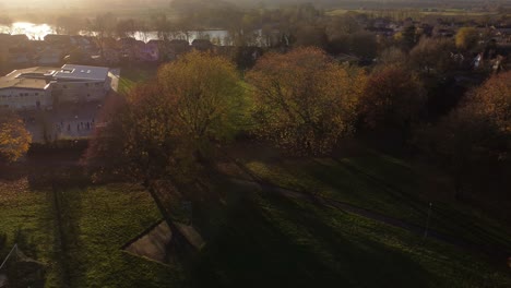 Autumn-sunset-trees-with-long-shadows-across-British-school-neighbourhood-aerial-view-with-sunbeams