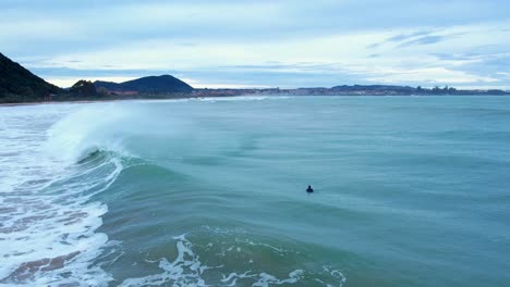 Drohnenaufnahme-Eines-Surfers,-Der-Am-Strand-Eine-Welle-überspringt